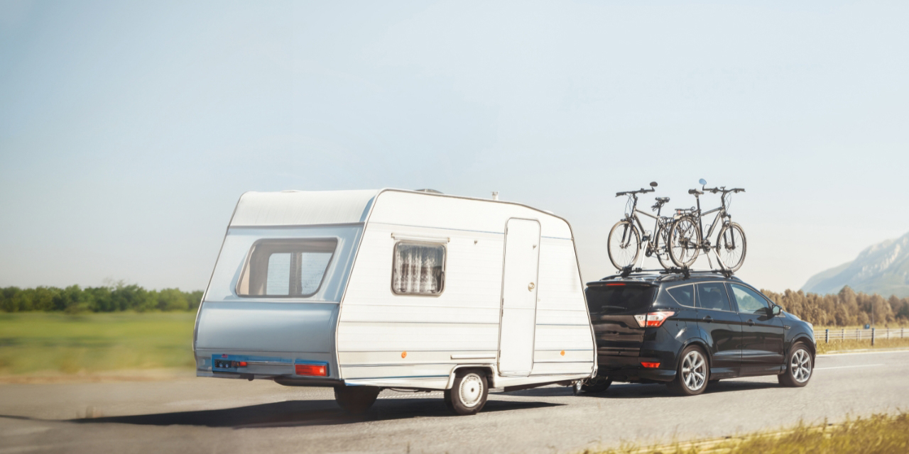 SUV pulling a camper and transporting bikes in roof rack.
