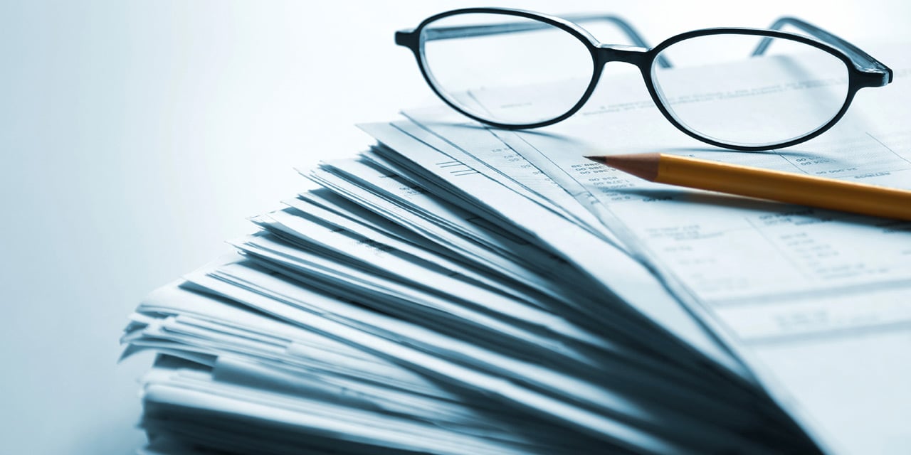 Mountain of papers with glasses and pencil on top