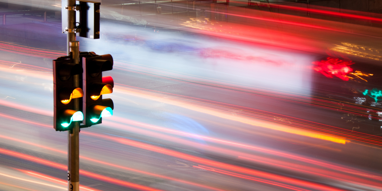 Traffic lights with abstract images of vehicle headlights and taillights as a background.