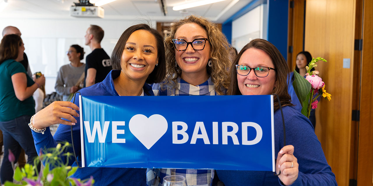 Three women holding a 'we love Baird ' banner