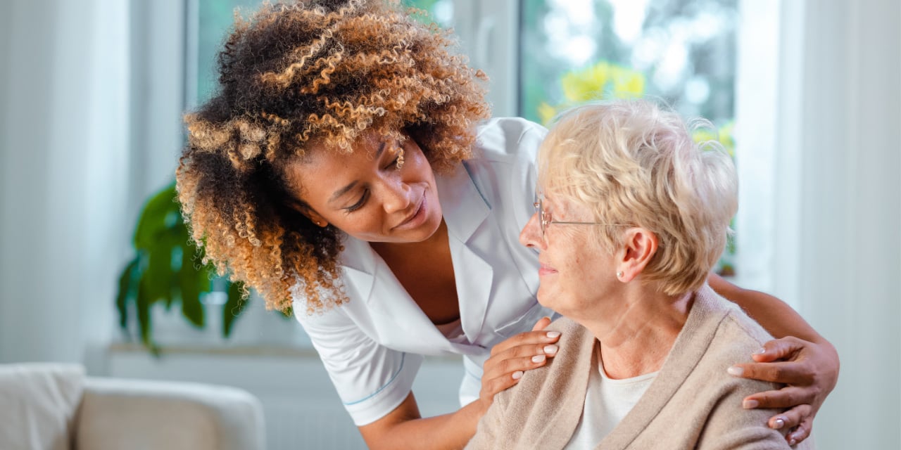 A caretaker speaking with an elderly woman